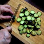 Personne découpant des courgettes sur une planche à découper