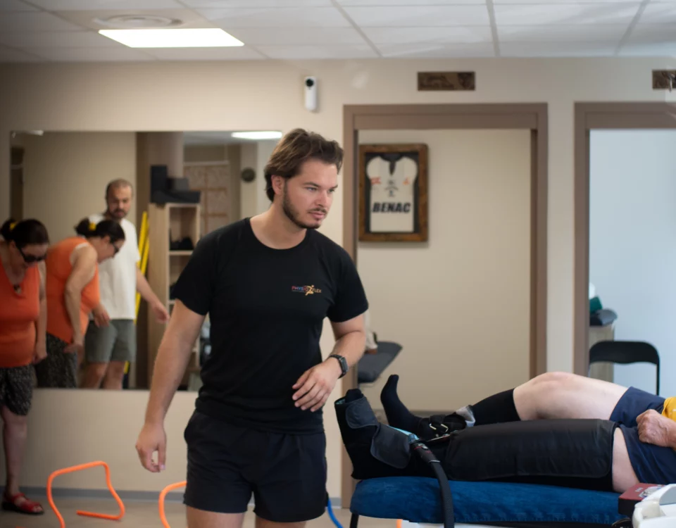 Photographie d'un cabinet de kinésithérapie, un kiné se dirige vers son patient allongé