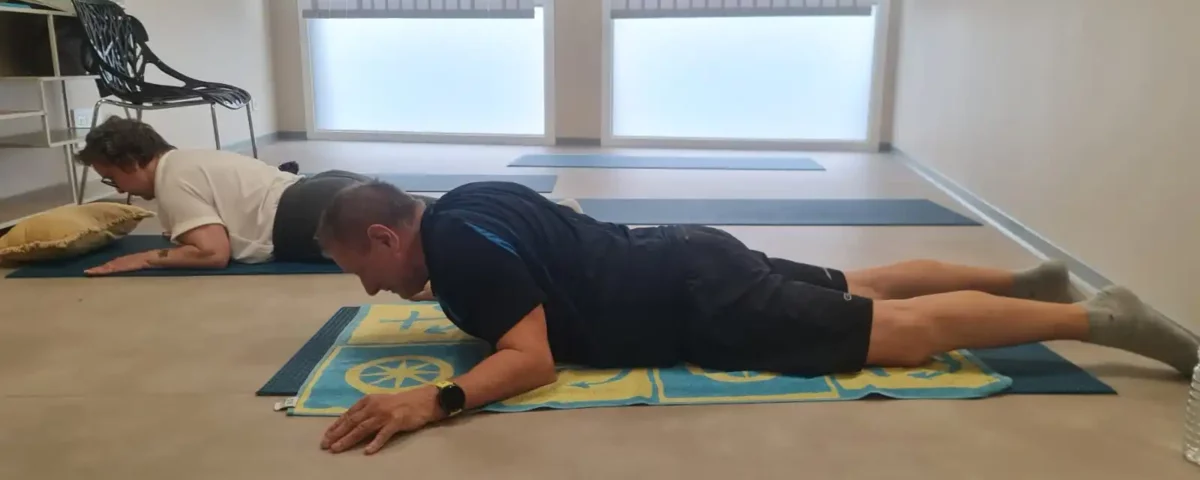 Deux personnes effectuant du gainage sur un tapis de yoga au sol dans une pièce