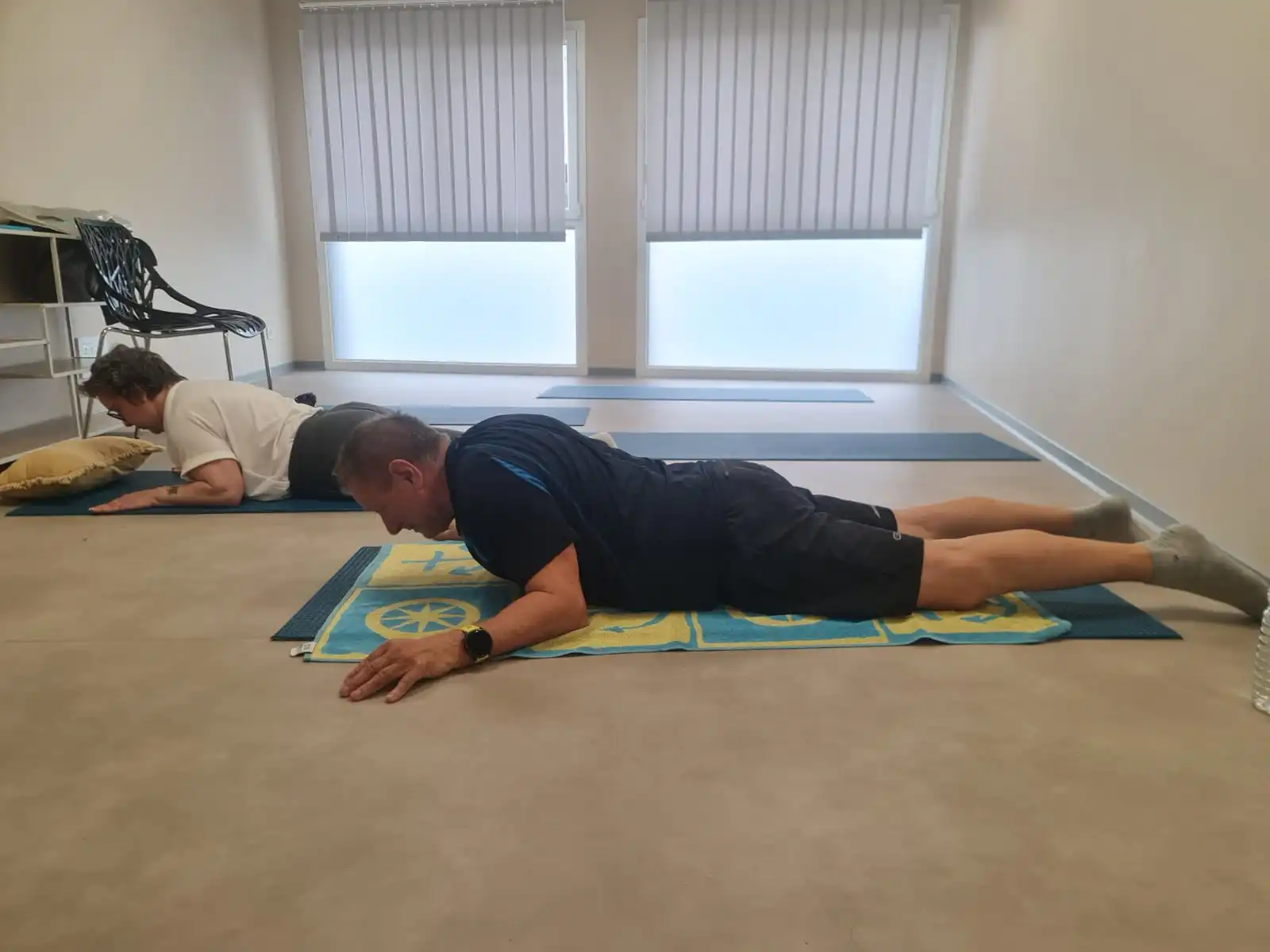 Deux personnes effectuant du gainage sur un tapis de yoga au sol dans une pièce