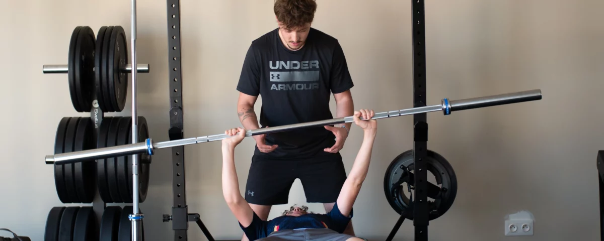 Kinésithérapeute aidant un patient à soulever une barre de musculation