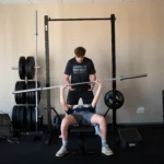 Kinésithérapeute aidant un patient à soulever une barre de musculation