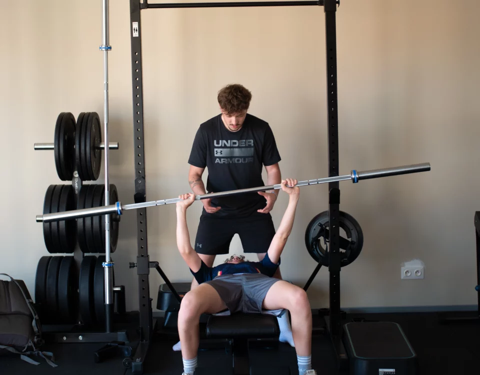 Kinésithérapeute aidant un patient à soulever une barre de musculation